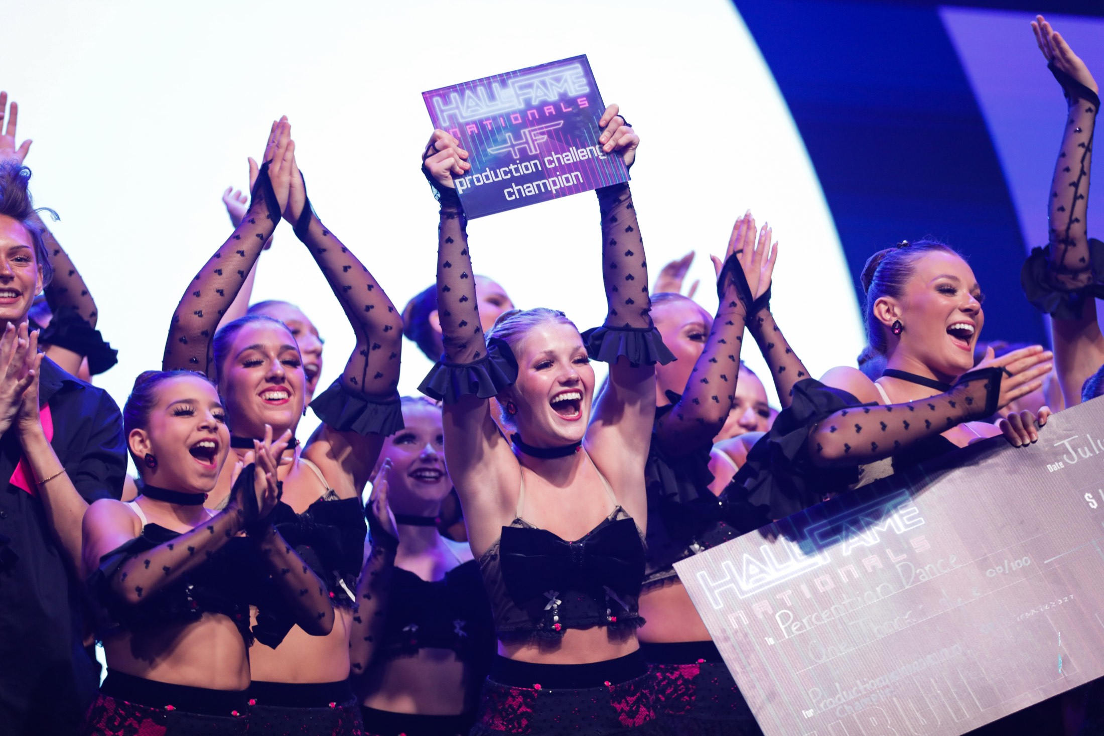 Dancers celebrating with their Production Challenge champion sign
