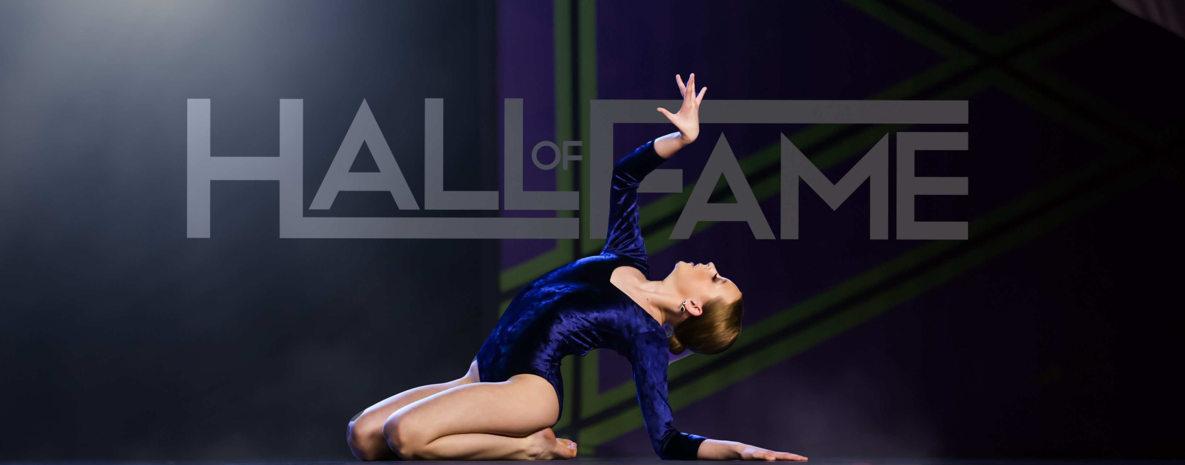 A soloist on one knee in front of the Hall of Fame logo