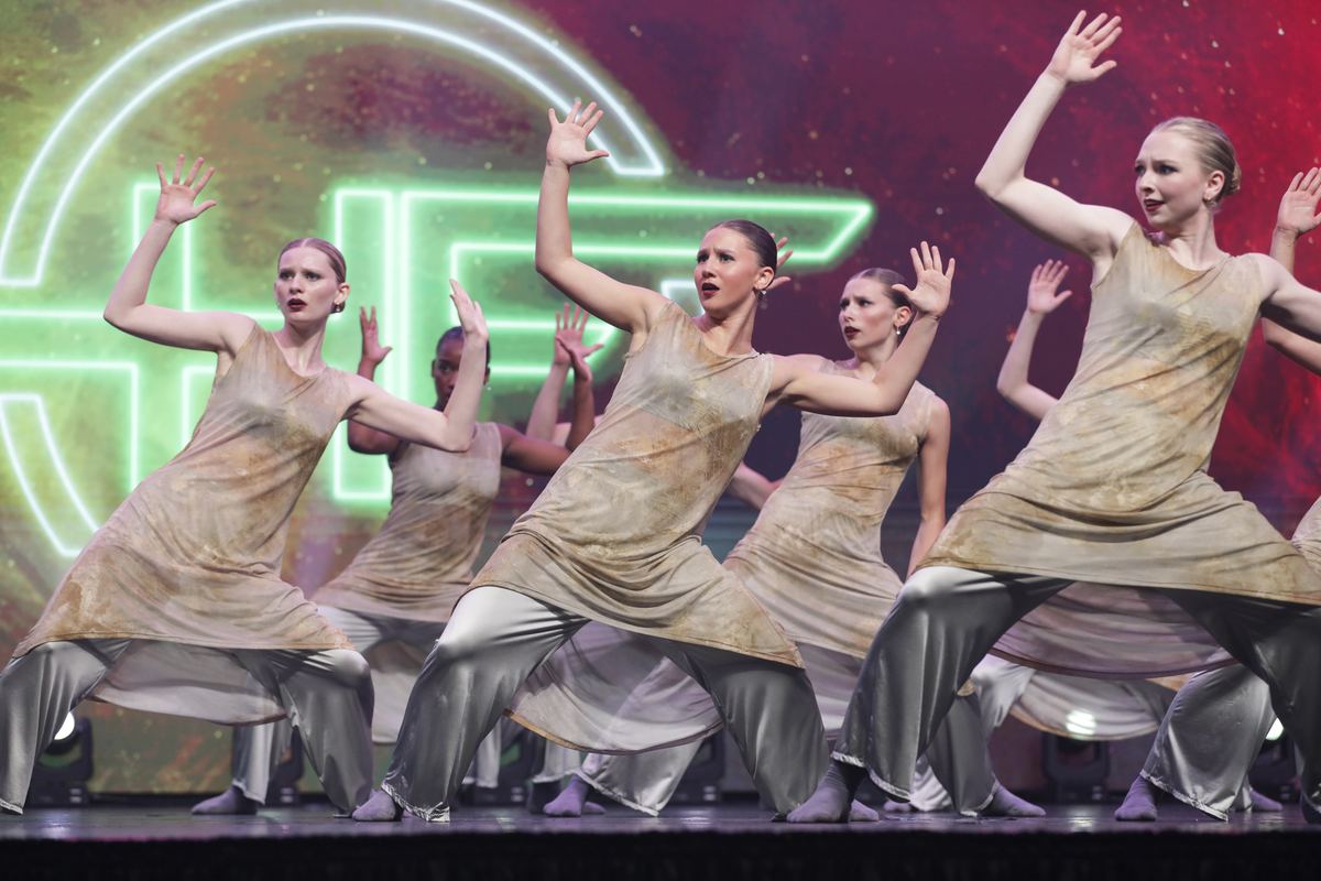 A group in flowing gold costumes reaching upward